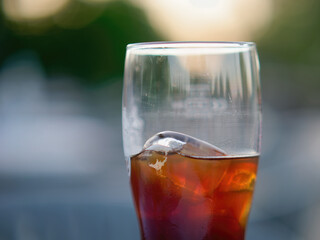 Selective focus shot of a glass of black Radler beer with ice with a blurry background