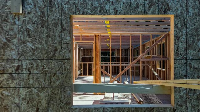 Moving through the interior of a modern home in mid construction phase, exiting through the front window to reveal the exterior in a natural forest setting