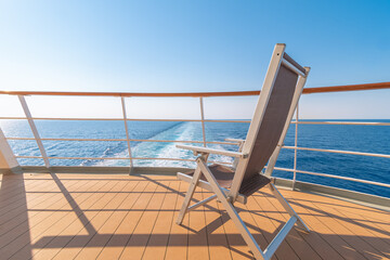 Obraz premium Vue d'une chaise longue sur le pont d'un navire de croisière dans le sillage d'un navire de croisière. Vue depuis la poupe du navire. 