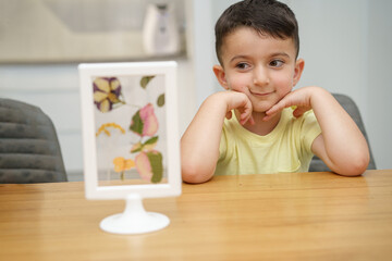 Child look at the herbarium frame. Selective focus on boy.