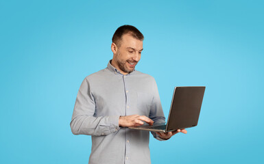 Happy Middle Aged Male Using Laptop Computer Over Blue Background
