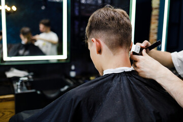 Teenage boy has a haircut in barbershop. Hairdresser job background
