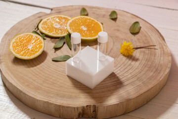 Frascos de vidrio transprente, pequeños, con tapa blanca, sin marca con hojas verdes y rebanadas de naranja sobre tabla de madera, toma de arriba