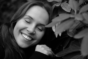 Obraz premium Brunette girl with closed eyes on the background of plantleaves