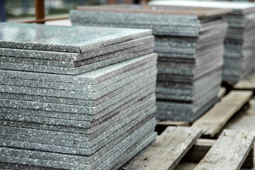 Stacks of gray stone tiles stacked on pallets for sale.