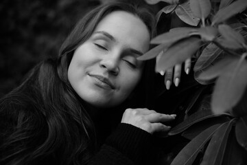 Brunette girl with closed eyes on the background of plantleaves