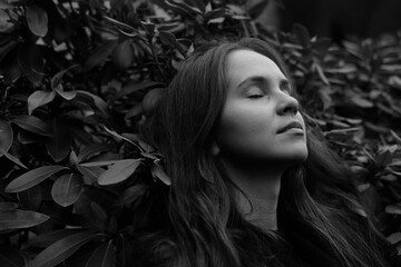 Brunette girl with closed eyes on the background of plantleaves