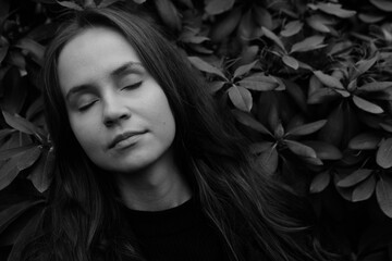 Brunette girl with closed eyes on the background of plantleaves