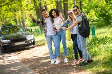 Group of young people hitchiking on the road