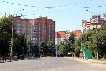 In summer, a city street with a three-lane road for cars.