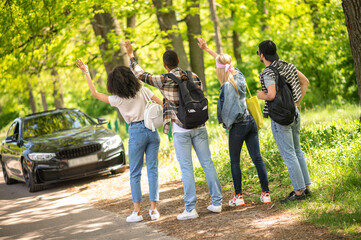 Group of young people hitchiking on the road