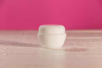 Fototapeta na wymiar Frasco de crema blanco, sin marca, con fondo rosa