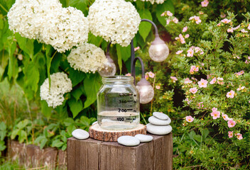 Handmade rain water gauge made of glass jar, measuring rain in home garden. Raining outdoors in...
