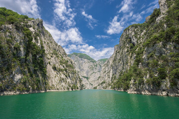 blue greenish lake between high mountains on a sunny day, komani lake in the albanian alps