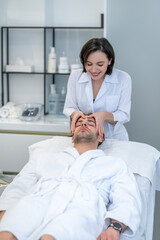 Obraz na płótnie Canvas Young male client having face massage in a professional salon