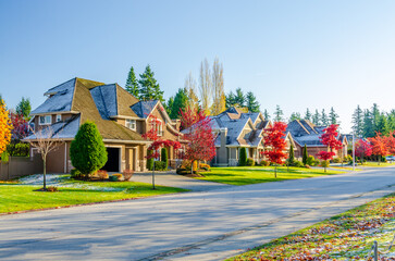 Neighbourhood of luxury houses with street road, big trees and nice landscape in Vancouver, Canada. Blue sky. Day time on September 2021.