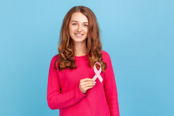 Lovely beautiful woman wearing pink pullover, holding pink ribbon, breast cancer awareness, female...