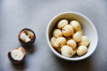 Delicious peeled Macadamia nut in a salad bowl on a gray background. The kernels of a delicious Macadamia nut close-up.