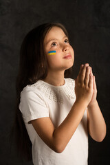 Fototapeta premium A little girl prays for Ukraine