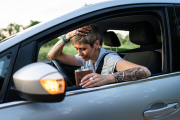 woman with flask drink alcohol while driving car drunk female driver