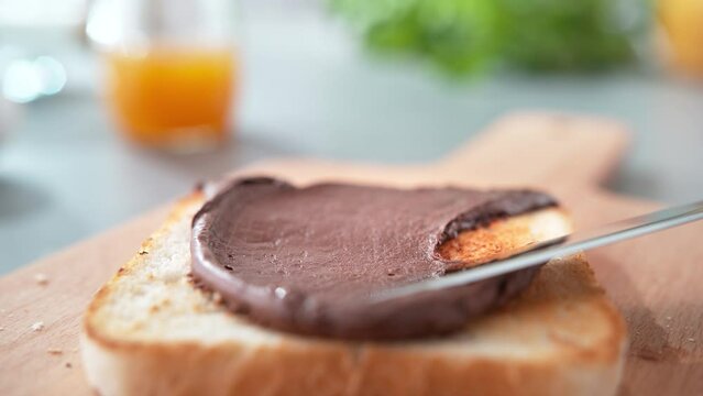 Spreading Chocolate Spread on a Slightly Browned Toast with Butter Knife on Cutting Board in Slow Motion