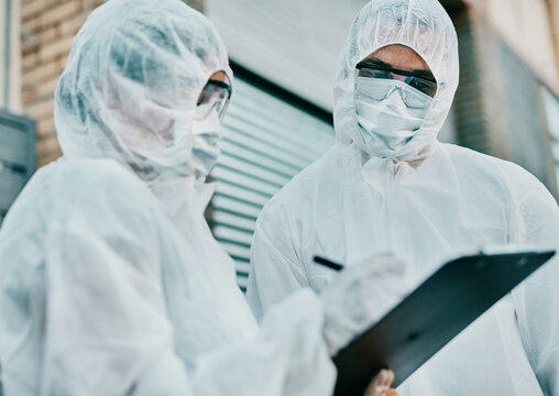 Healthcare Workers Wearing Protective Hazmat Suits Writing A Medical Report About Covid Cases Or Statistics. First Responders Filling In A Form After Doing A Safety Health Check For Coronavirus