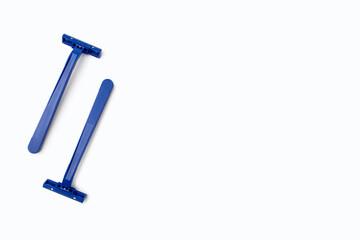 Two blue plastic razors are located on a white background. Disposable blue plastic razors lie on a white background with free space for text or advertising. Tool for shaving and smooth skin care