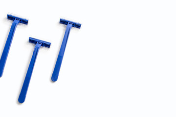 Three blue plastic razors on a white background. Disposable blue plastic razors lie on a white background. Shaving and care product for smooth skin. Free space for text