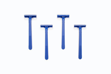 Four blue plastic razors on a white background. Disposable blue plastic razors lie on a white background. Shaving and care product for smooth skin. Razor without replaceable blades