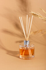 reed diffuser bottle on a beige background. Incense sticks for the home with a floral scent. The...