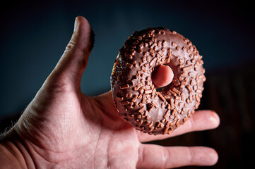 close-up of fresh sweet donuts on human finger