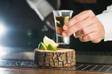 Tequila. a man holds a glass of tequila shot, the trend drinks concept.