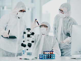 Group of doctors and scientists conducting medical research on viruses dressed in hazmat suits, for...