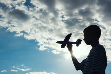 Teenage boy throwing airplane to the sky on summer evening. Childhood dreams, summer holiday entertainment outdoors