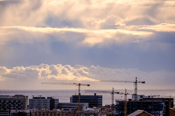 Skyline of the city of Barcelona (Spain) with various cranes of new constructions and the sea in the background.