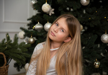 portrait of a christmas girl with christmas tree in a white dress