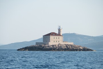 Fototapeta na wymiar lighthouse at a small rocky island in sea