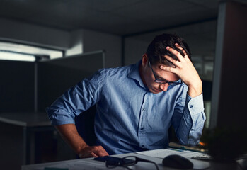 Obraz premium Stressed, tired business man suffering from headache, working late night in the office. Worried male entrepreneur thinking about problems and project deadline feeling burnout, distress and exhausted.