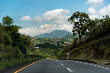Fototapeta na wymiar Road between small hills with mountain landscape in the background. Colombia.