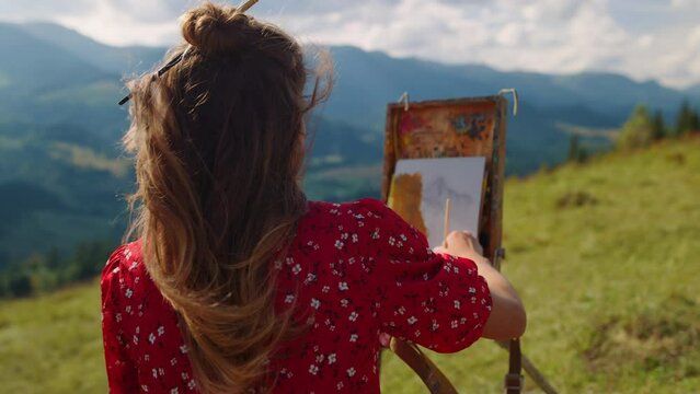 Woman creating picture nature on mountains hill closeup. Girl drawing on meadow.