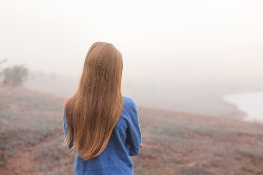 girl walking on a foggy morning, back view - Powered by Adobe