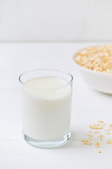 bowl of granola with a spoon and a glass of oat milk. white wooden background. top view. copy space.