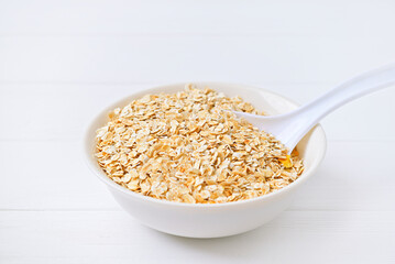 bowl of granola with a spoon. white wooden background.
