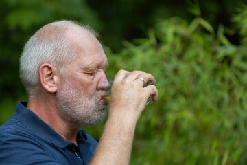 Obraz premium old man is drinking softdrink in the garden