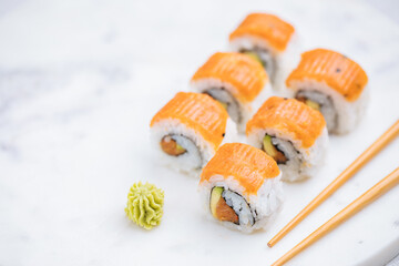 Sushi rolls on platter, bright background. Served with wasabi and ginger. Assorted Japanese sushi. Traditional food. 
