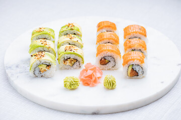 Sushi rolls on platter, bright background. Served with wasabi and ginger. Assorted Japanese sushi. Traditional food. 