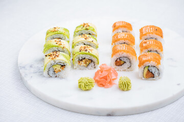 Sushi rolls on platter, bright background. Served with wasabi and ginger. Assorted Japanese sushi. Traditional food. 