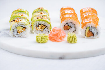 Sushi rolls on platter, bright background. Served with wasabi and ginger. Assorted Japanese sushi. Traditional food. 
