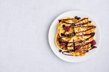 American pancakes decorated like smile and happy faces with raspberries, blueberries and banana. Food for kids, playful and creative. Top view.