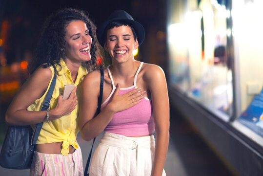 Young Women Window Shopping While Going Out In Town At Summer Night